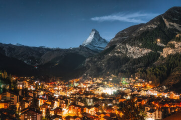 Zermatt village with light glowing and Matterhorn peak in the night at Switzerland