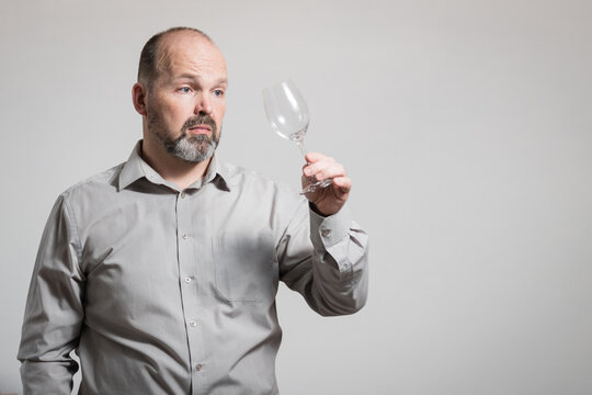 Caucasian man staring at empty wine glass, white background. Conceptual image of The Dry Challenge