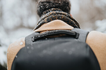 A detailed view of a young business professional clad in winter clothing, with snowflakes gently...