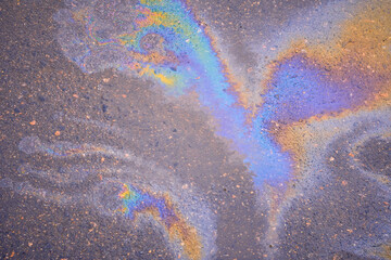 Texture of colorful petrol oil spill on wet pavement. Slick industry oil fuel spilling water pollution