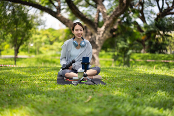 Fototapeta premium Female Social Media Influencer Demonstrates Massage Gun Usage in a Serene Park Setting
