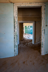 Fototapeta na wymiar Open door reveals a room with sandy floor, in an old deserted town