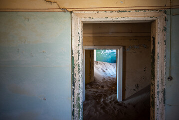 Fototapeta na wymiar Open door leading to an abandoned hallway, with a dune covering the ground