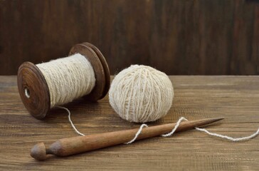 Balls of wool yarn, old spool of thread and spindle on wooden background top view close-up.
