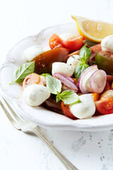 Summer Salad with Mozzarella Cheese, Tomatoes and fresh Basil. Bright wooden background.	