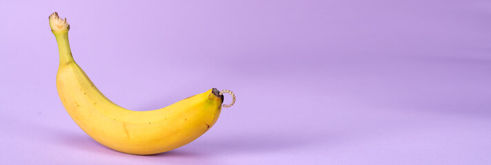 Intimate piercing. Minimal piercing concept. Banana with piercing on a lilac background