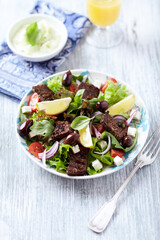 Salad with Grilled Beef Pieces, Cherry Tomatoes, feta Cheese and Kalamata Olives. Bright wooden background. Close up.	