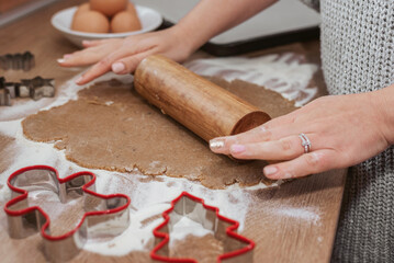 Close-up photo of hands using rolling pin on cookie dough for christmas cookies