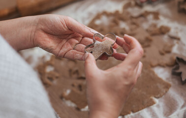 Close-up photo of hands using gingerbread man cookie cutter