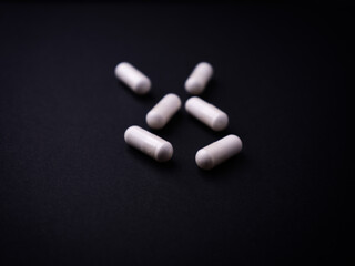 Creatine capsules on dark paper background. Soft focus. Close up. Copy space