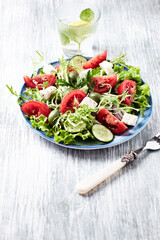 Salad with Green Olives, Tomatoes and Feta Cheese. Bright wooden background. Close up.	
