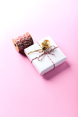 Christmas golden bauble and Christmas present. Bright paper background. Close up. Copy space.	