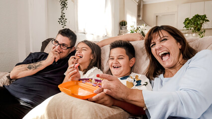 Happy family watching television while eating candies at home