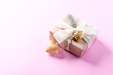 Christmas golden bauble and Christmas present. Bright paper background. Close up. Copy space.	