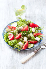 Salad with Green Olives, Tomatoes and Feta Cheese. Bright wooden background. Close up. 