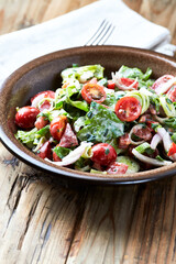 Simple Salad with Cherry Tomatoes, Lettuce, Red Pepper, Leek and Onion. Dark wooden background. 
