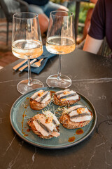 two glasses of white wine and sandwiches with fish on a plate on the table in an outdoor cafe or restaurant near the sea