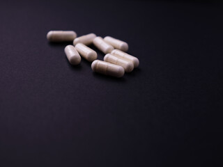 Creatine capsules on dark paper background. Soft focus. Close up. Copy space.	