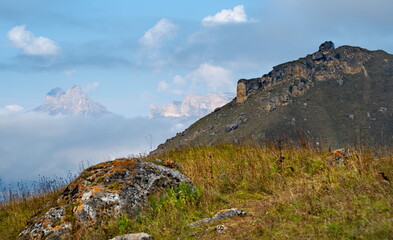 Russia. The Elbrus region. The high mountain peaks of the North Caucasus are surrounded by morning misty clouds hovering at different levels of inaccessible rocks.