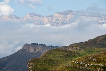Russia. The Elbrus region. The high mountain peaks of the North Caucasus are surrounded by morning misty clouds hovering at different levels of inaccessible rocks.
