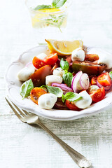 Summer Salad with Mozzarella Cheese, Tomatoes and fresh Basil. Bright wooden background.