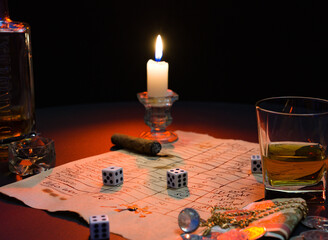 A game of dice. Still life with a burning candle on the table, with a glass of strong alcohol and dice.
