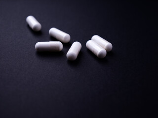 Creatine capsules on dark paper background. Soft focus. Close up. Copy space.
