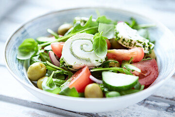 Summer Salad with Cream Cheese, green Olives, Tomatoes and fresh Basil. Bright wooden background. Close up