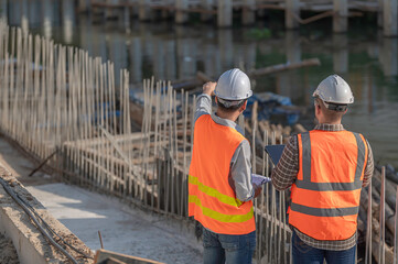 Construction engineer working on a bridge construction site over a river,Civil engineer supervising...