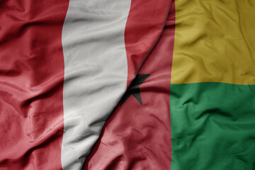 big waving national colorful flag of guinea bissau and national flag of peru .
