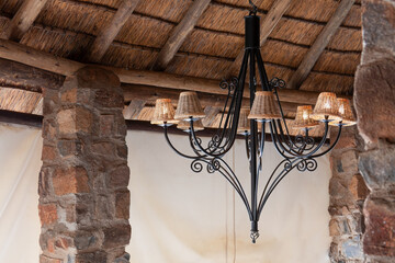 forged iron chandelier, room with thatched roof and stone columns, retro style