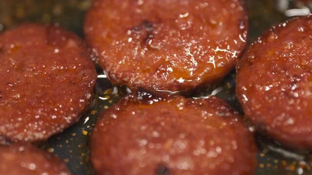 Cooking Turkish Sausage Also Known as Sucuk in Pan. Unrecognizable Person Flipping Sliced Meats to Roast Perfectly. Preparing for Breakfast Close Up Shot Slow Motion. Camera Moving Left to the Right. 