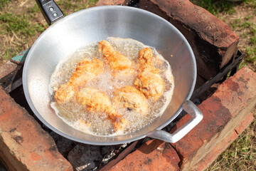 Chicken legs in batter are fried in a wok. Cooking outside