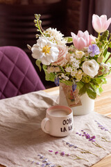 a beautiful delicate spring white and pink bouquet of tulips, buttercups and muscari. floral arrangement with coffee mug, festive morning