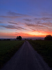Sunset over fields and cityscape with boy walking on path