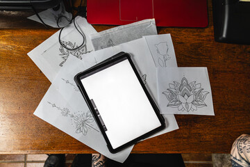 Horizontal photo artist's workspace with tattoo designs and digital tablet. Concept business, art.