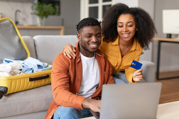 african couple using laptop and credit card booking tour indoor - obrazy, fototapety, plakaty