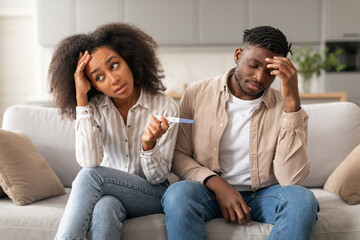 Upset Child Free African Couple Holding Positive Pregnancy Test Indoors
