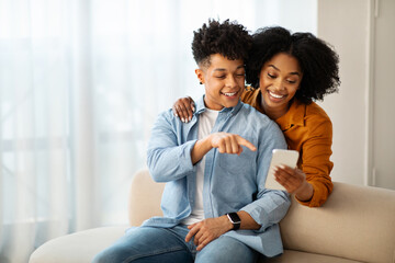 Fototapeta premium A young man in a denim shirt and a woman in a mustard top are sitting on a couch
