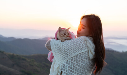 Travel concept with a pet.Cute asian girl on the mountain hugs her bengal cat.young woman with a cat on the mountain in morning 