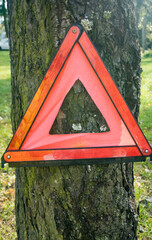 Red triangle, red emergency stop sign, red emergency symbol. On a tree.