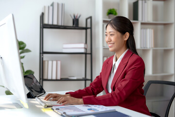 Confident young Asian businesswoman sitting and working with laptop computer in office.