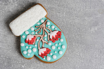 Christmas cookies in shape mitten, decorated with icing depicting rowan tree, sprinkled with snow. Magic holiday every sweet detail.