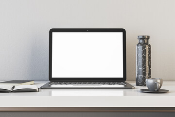 Modern designer office interior with white mock up laptop, coffee cup, notepad and vase. Concrete wall background. Workplace and close up concept. 3D Rendering.