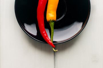 One and a half hot peppers on a black round plate.