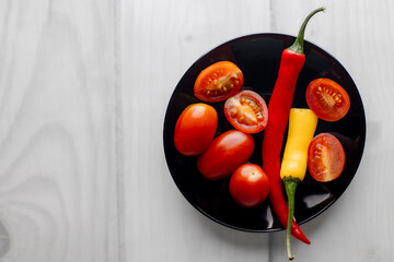 One and a half hot peppers on a black round plate.