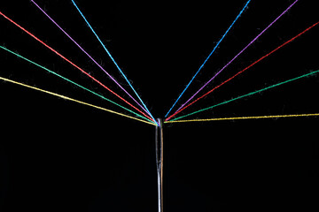 Eye sewing needle and multicolored threads passed through it black background. Concept hobbies and...