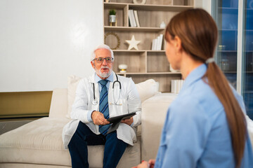 Obraz premium Senior man doctor examining young woman in doctor office clinic or at home. Girl patient and doctor have consultation in hospital room. Medicine healthcare medical checkup. Visit to doctor