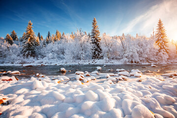 Gorgeous view of a calm river with snow-covered stones on a frosty day.