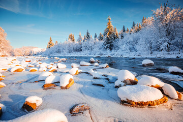 Gorgeous view of a calm river with snow-covered stones on a frosty day.